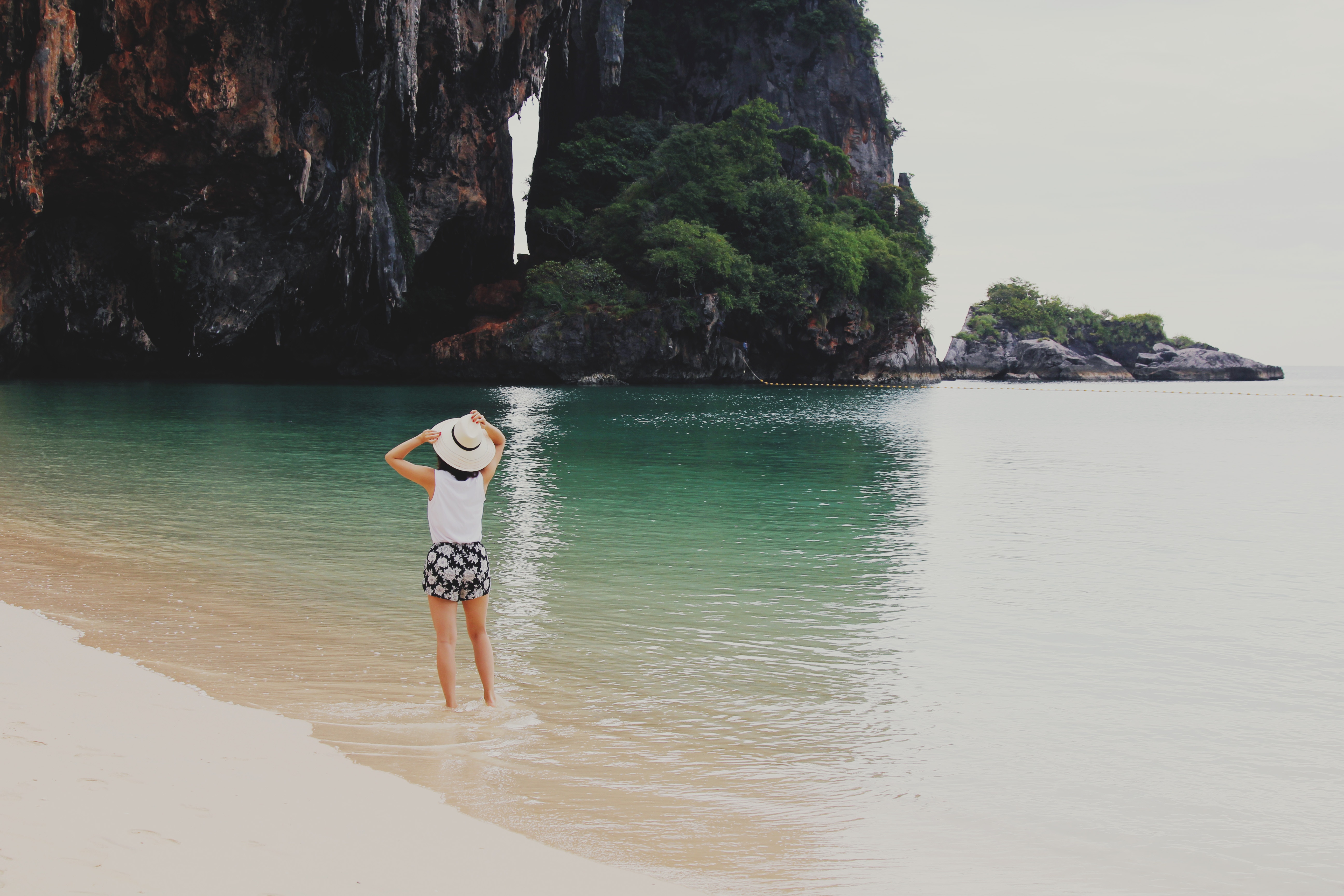 femme en voyage, de dos, probablement vietnam, en Asie, plage, rocher, pieds dans l'eau