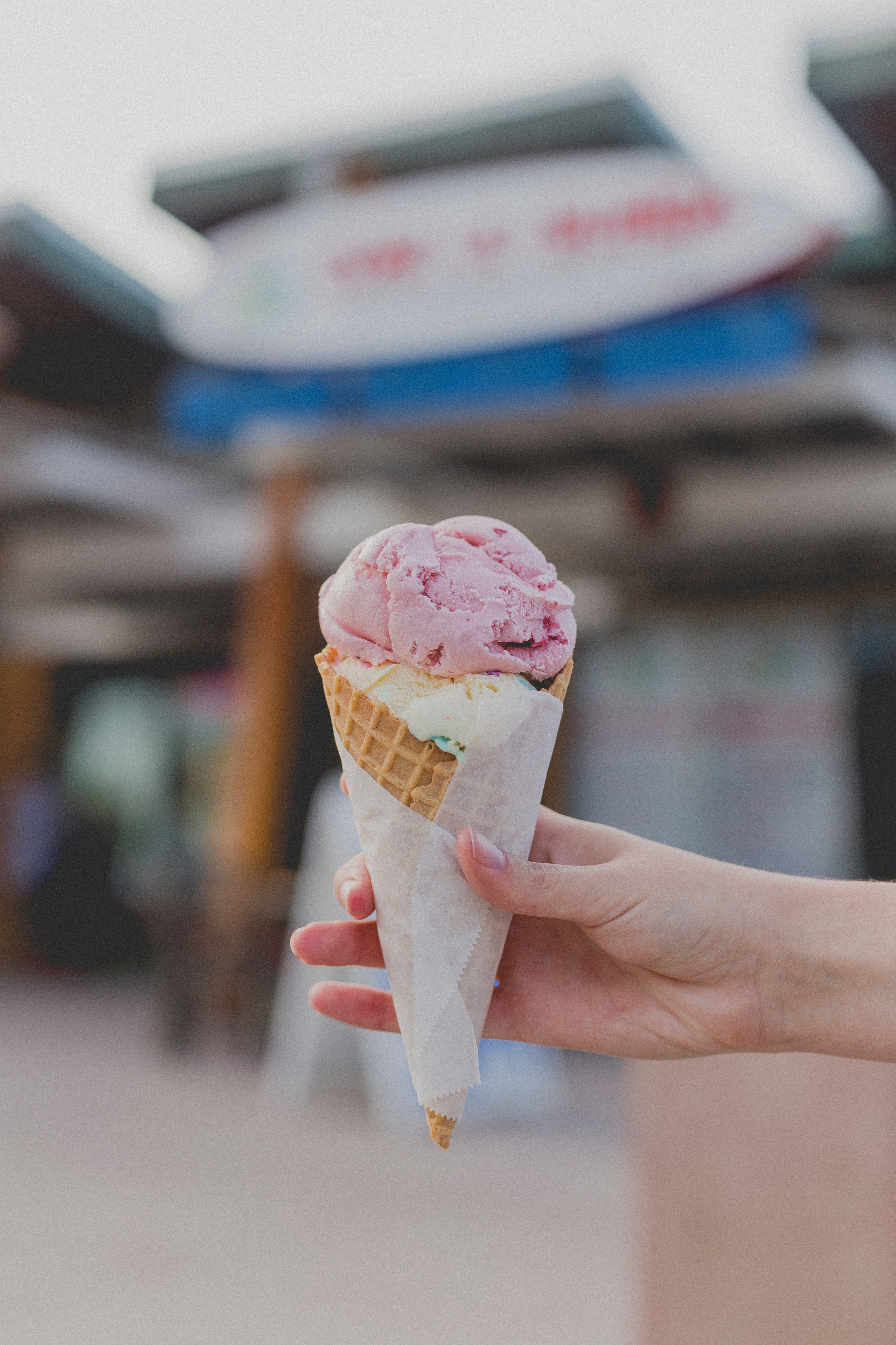 main tenant une crème glacée vanille et fraise dans un cornet gaufré