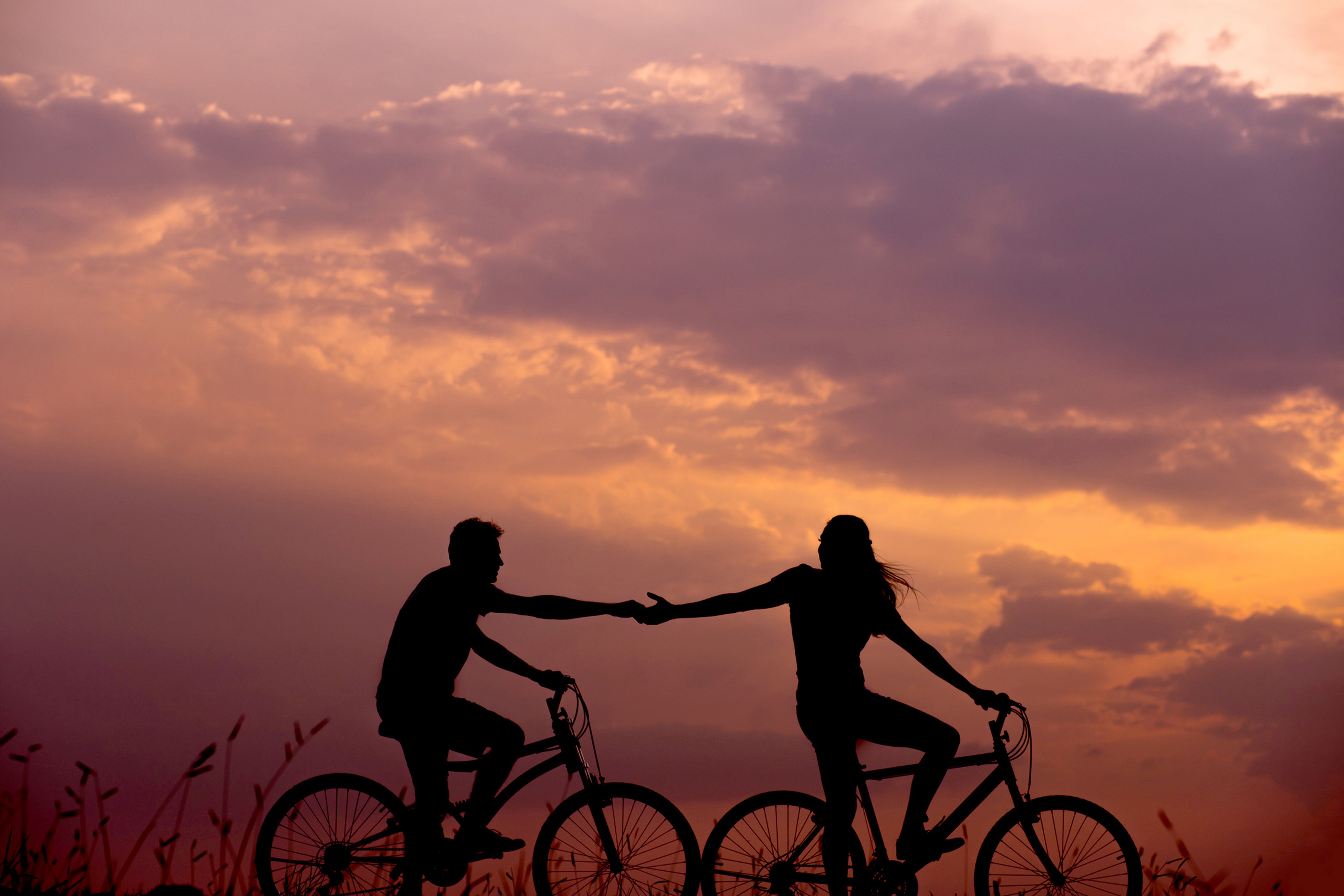 couple tenir la main vélos coucher de soleil
