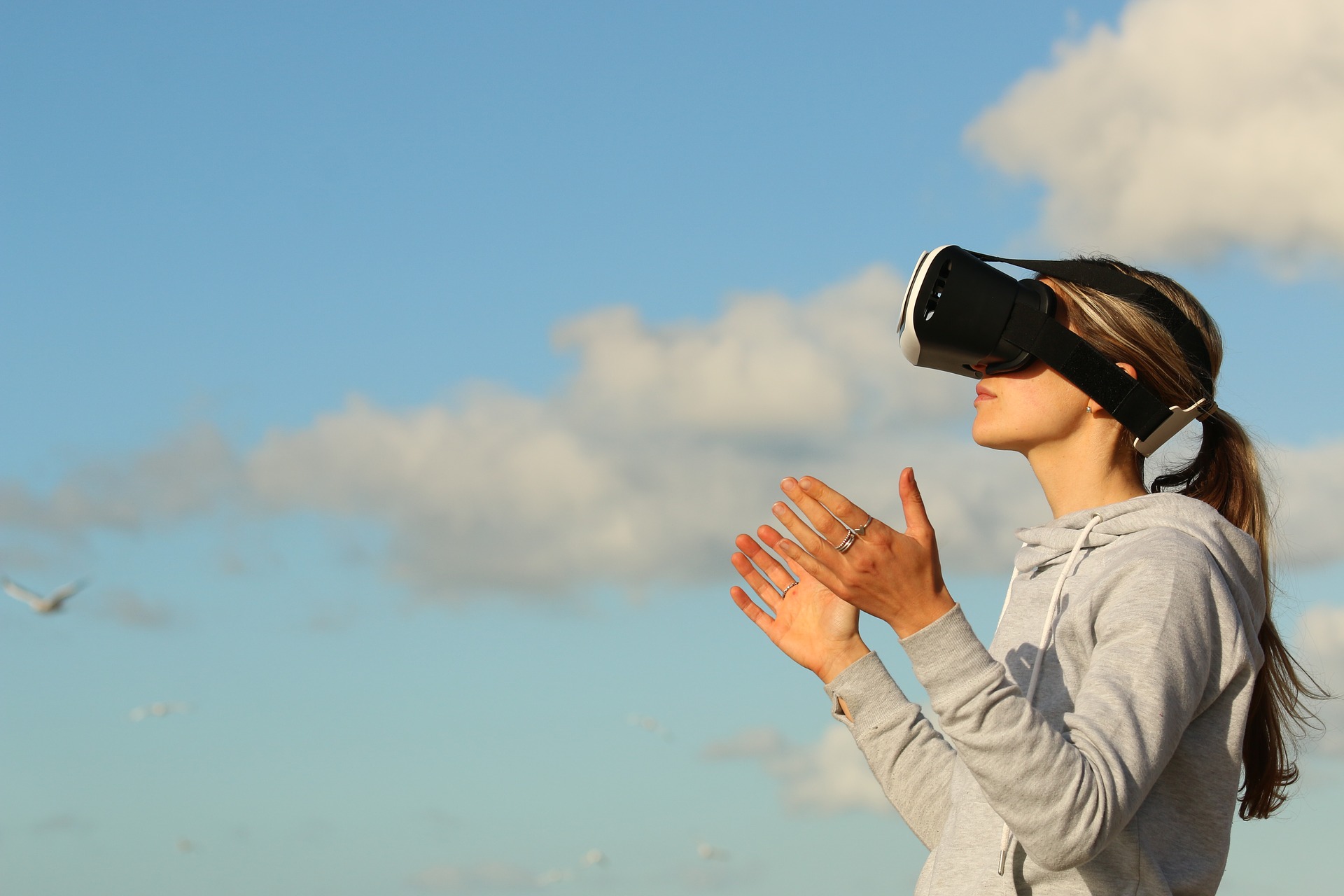 une fille qui porte un casque de réalité virtuelle et derrière elle on peut voir le ciel