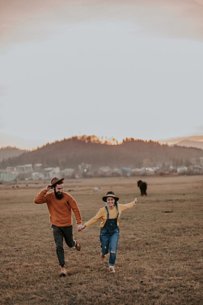 homme et femme qui courent dans un champ en riant