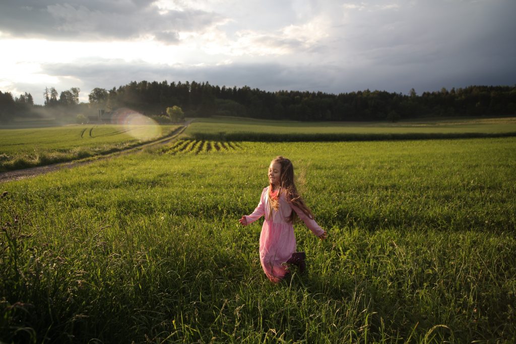 jeune fille qui court dans un champ avec une robe rose