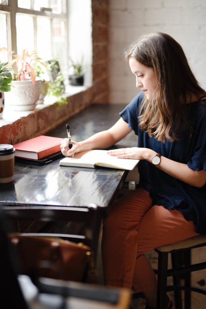 jeune femme qui écrit dans un café