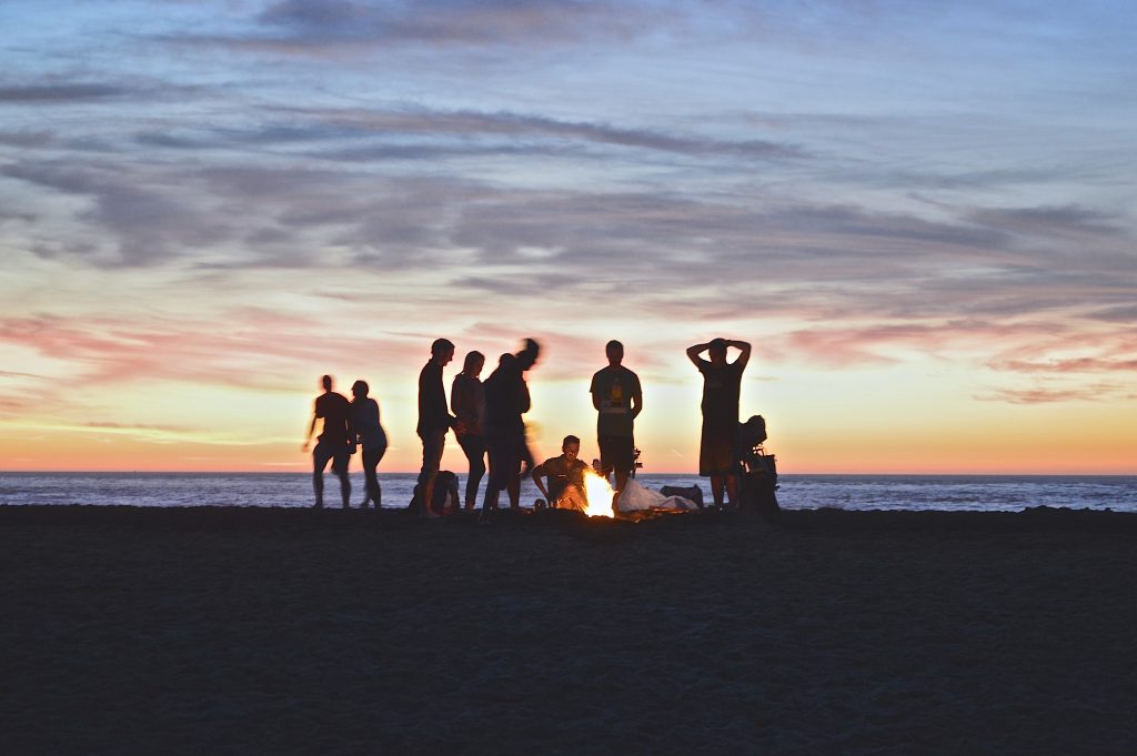groupe de personnes sur la plage en train de faire un feu de camp