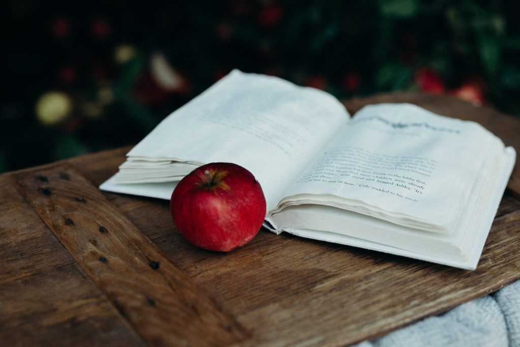 livre ouvert avec pomme à côté