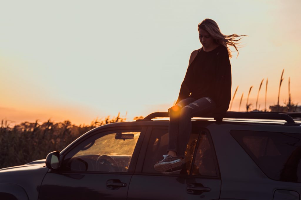 fille cheveux dans le vent assise sur toit voiture