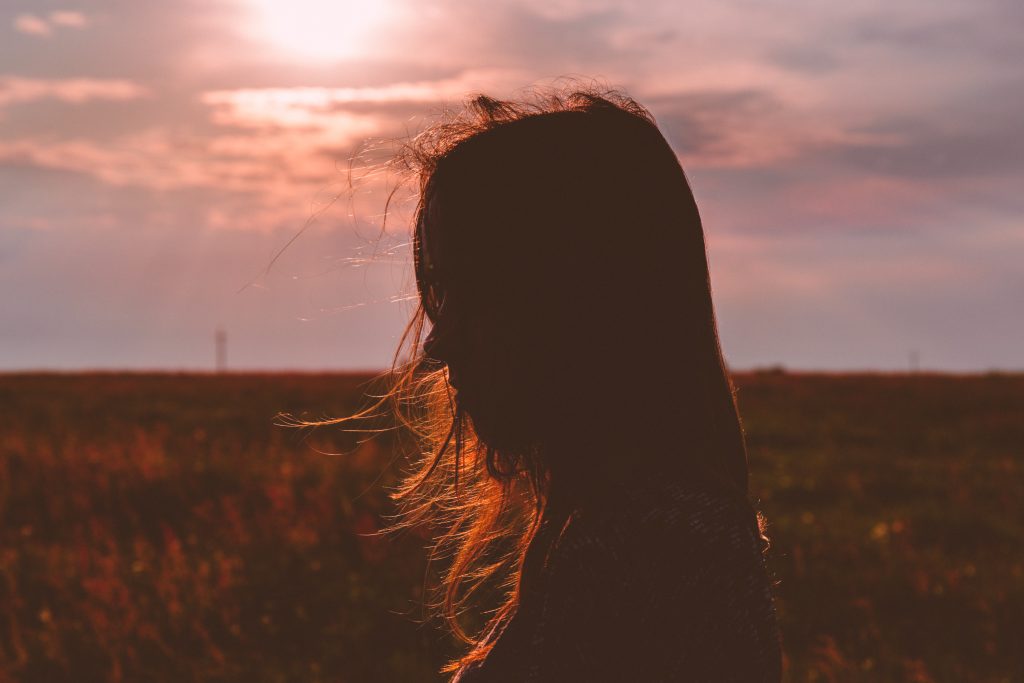 femme de profil cheveux dans le vent coucher de soleil