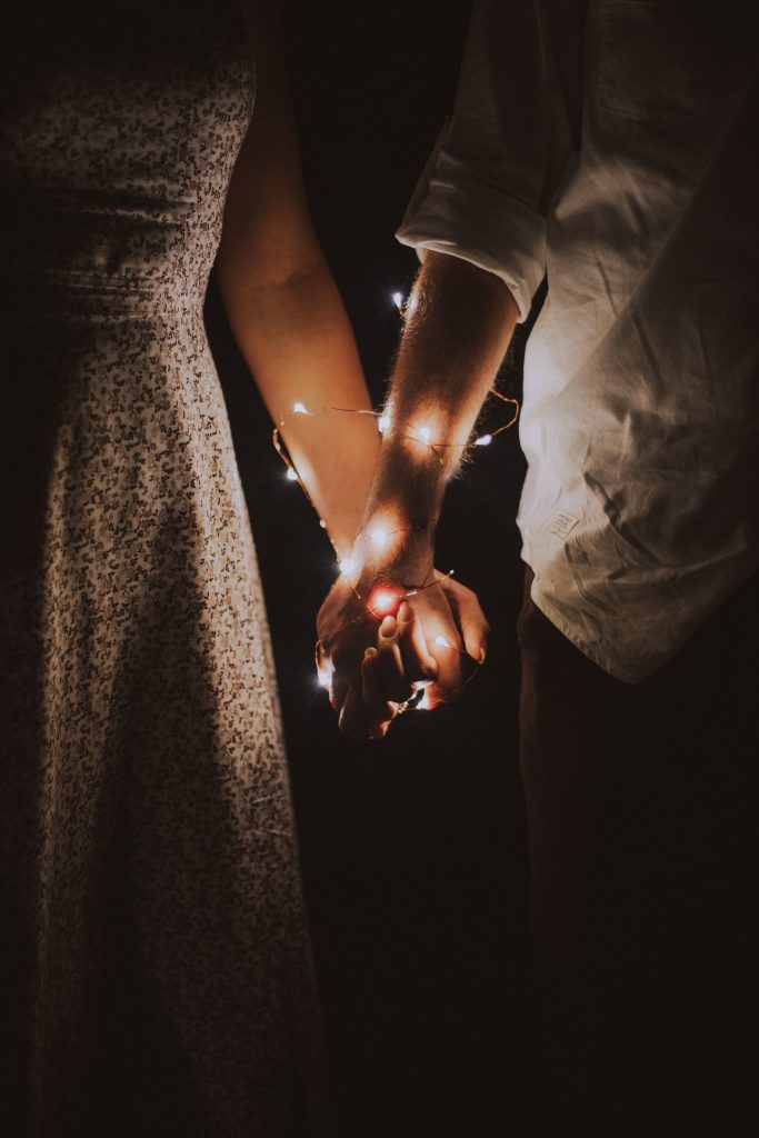 homme et femme se tiennent la main lumières