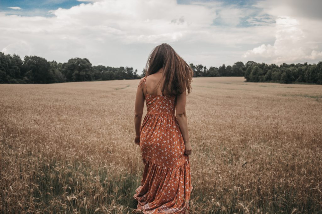 femme robe fleurie de dos devant champ