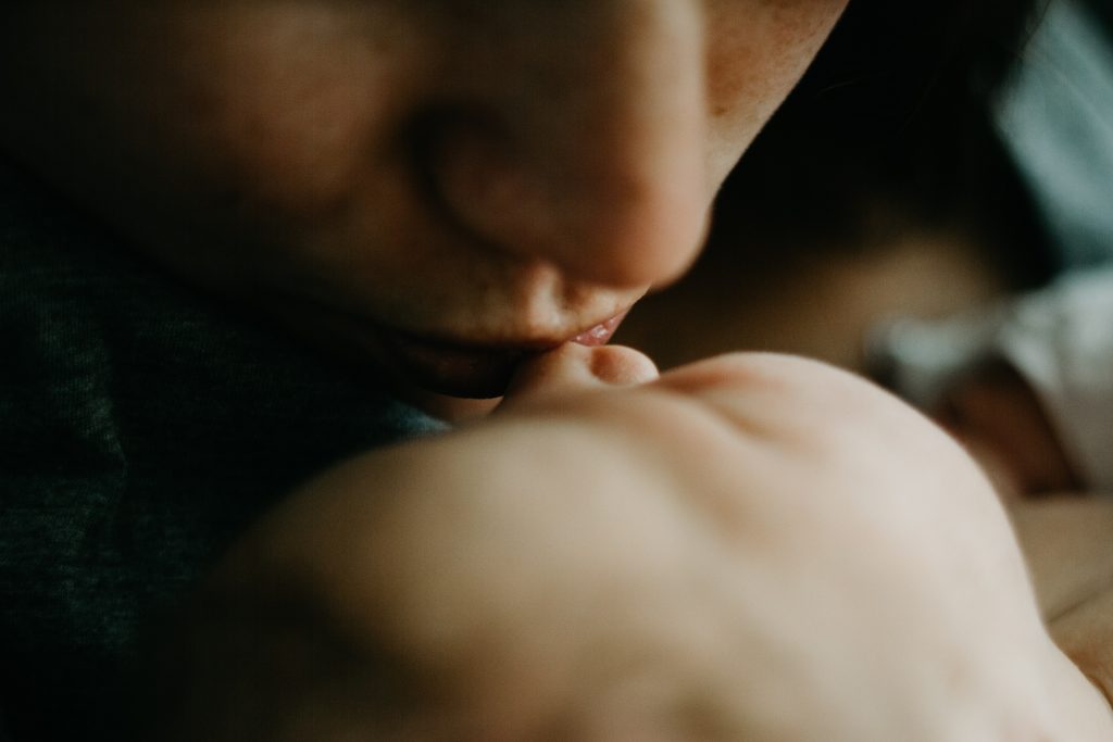 bouche de maman qui embrasse son bébé sur le front