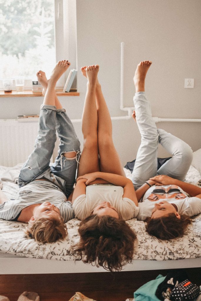 3 filles couchées sur un lit, jambes en l'air