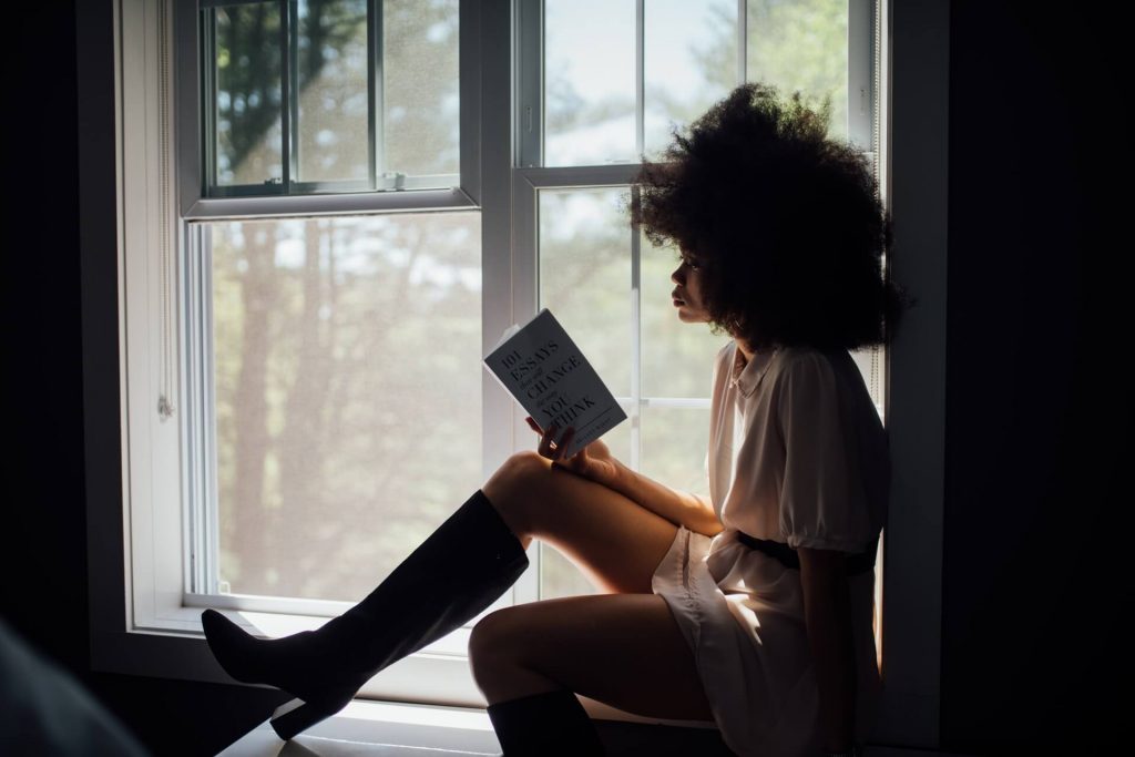 femme qui lit un livre sur le bord de la fenêtre