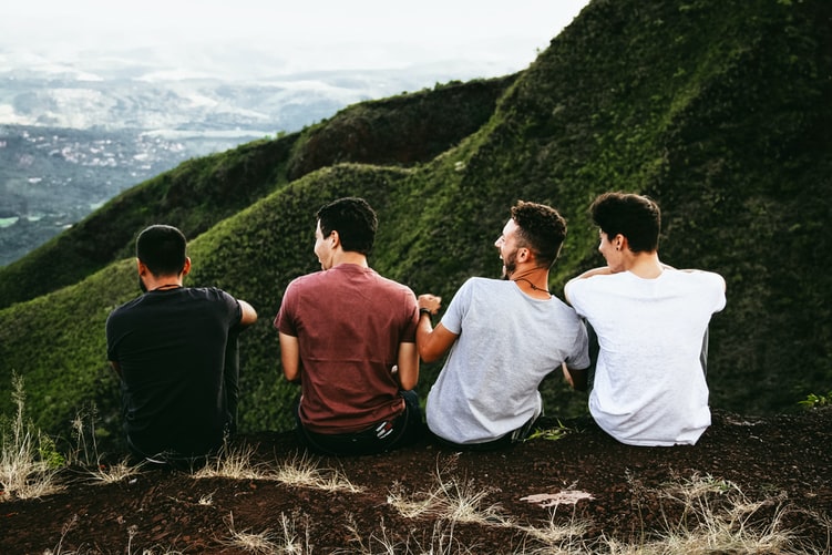 Rangée de quatre hommes assis sur un sentier de montagne