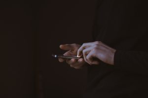 mains qui tiennent un téléphone sur fond noir